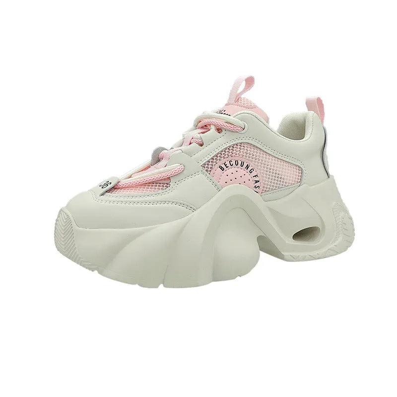 Women's pink sneakers with a cross strap and thick sole on a neutral background.