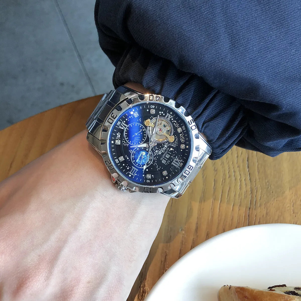 Men's silver automatic watch with black starry luminous dial on a leather strap.