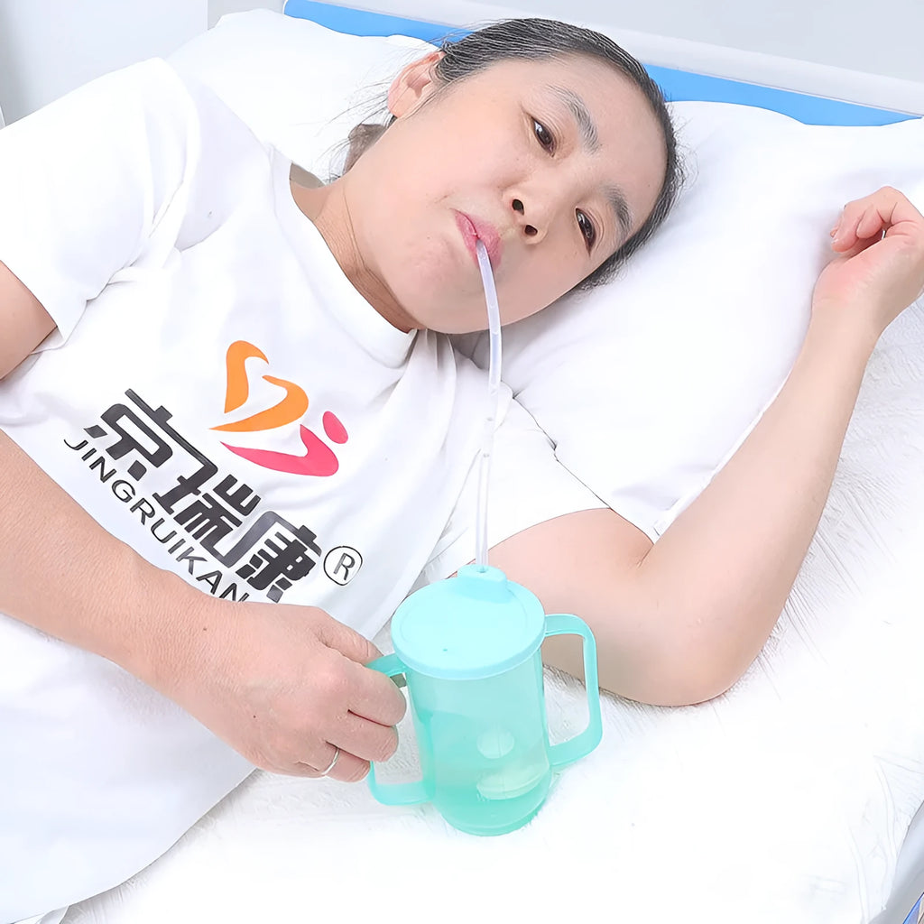 Adult angled spout anti-choke drinking cup with handle and lid, shown with optional wrist splint attachment