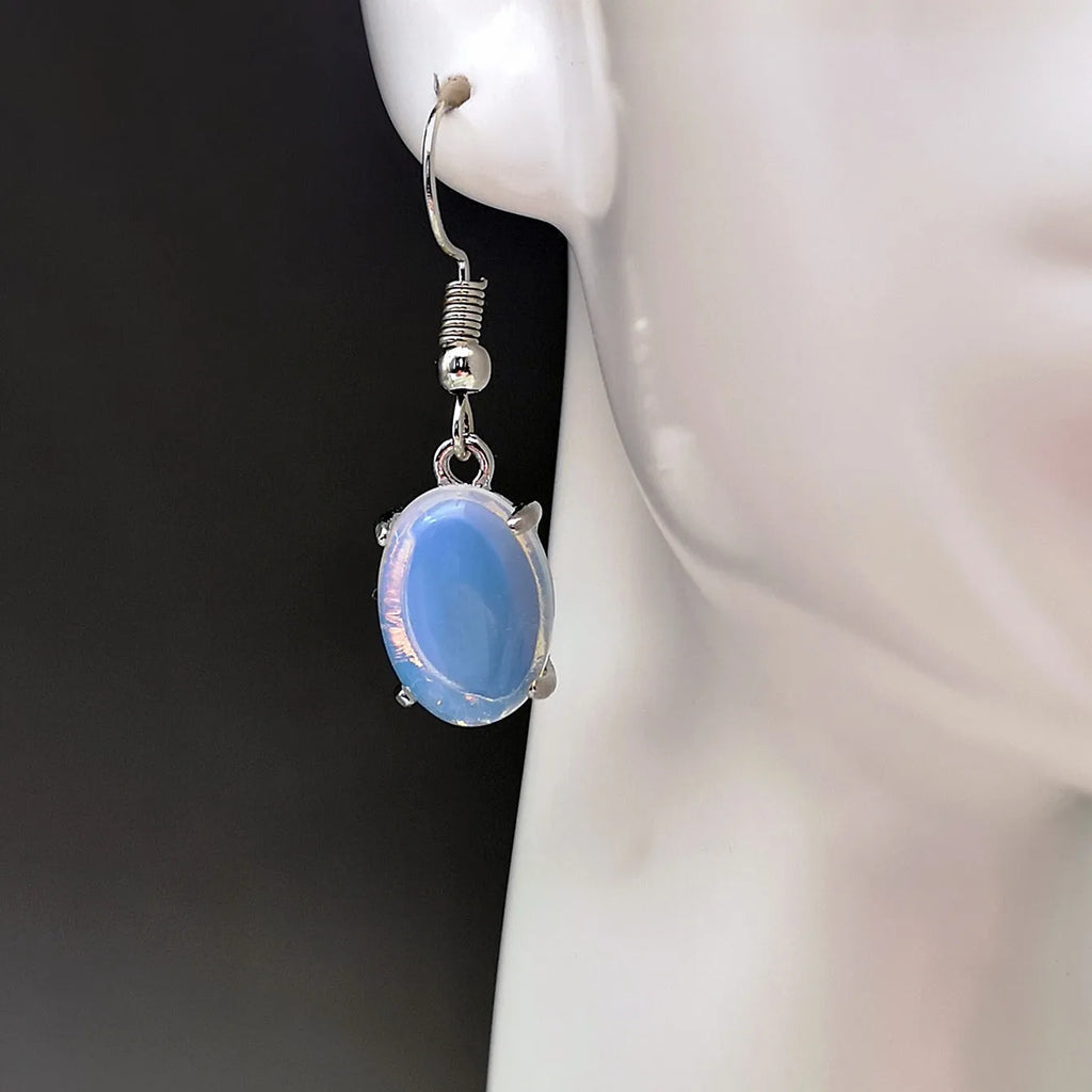 Close-up of moonlight white opal drop earrings with a cross pendant on an alloy post.