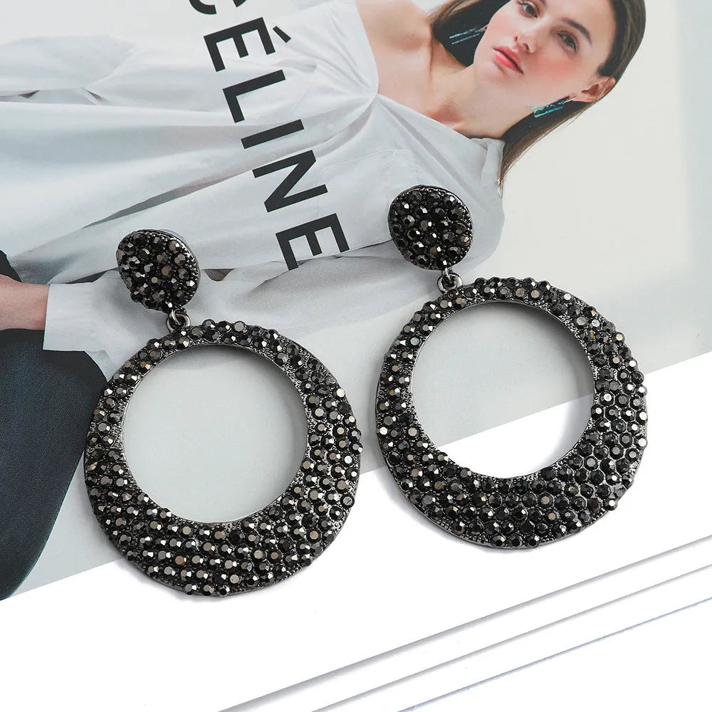 A pair of large round metal alloy pendant earrings with colourful cartoon diamond decorations.