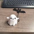 Small white resin statue of a ghost walking a bat on a Halloween lead