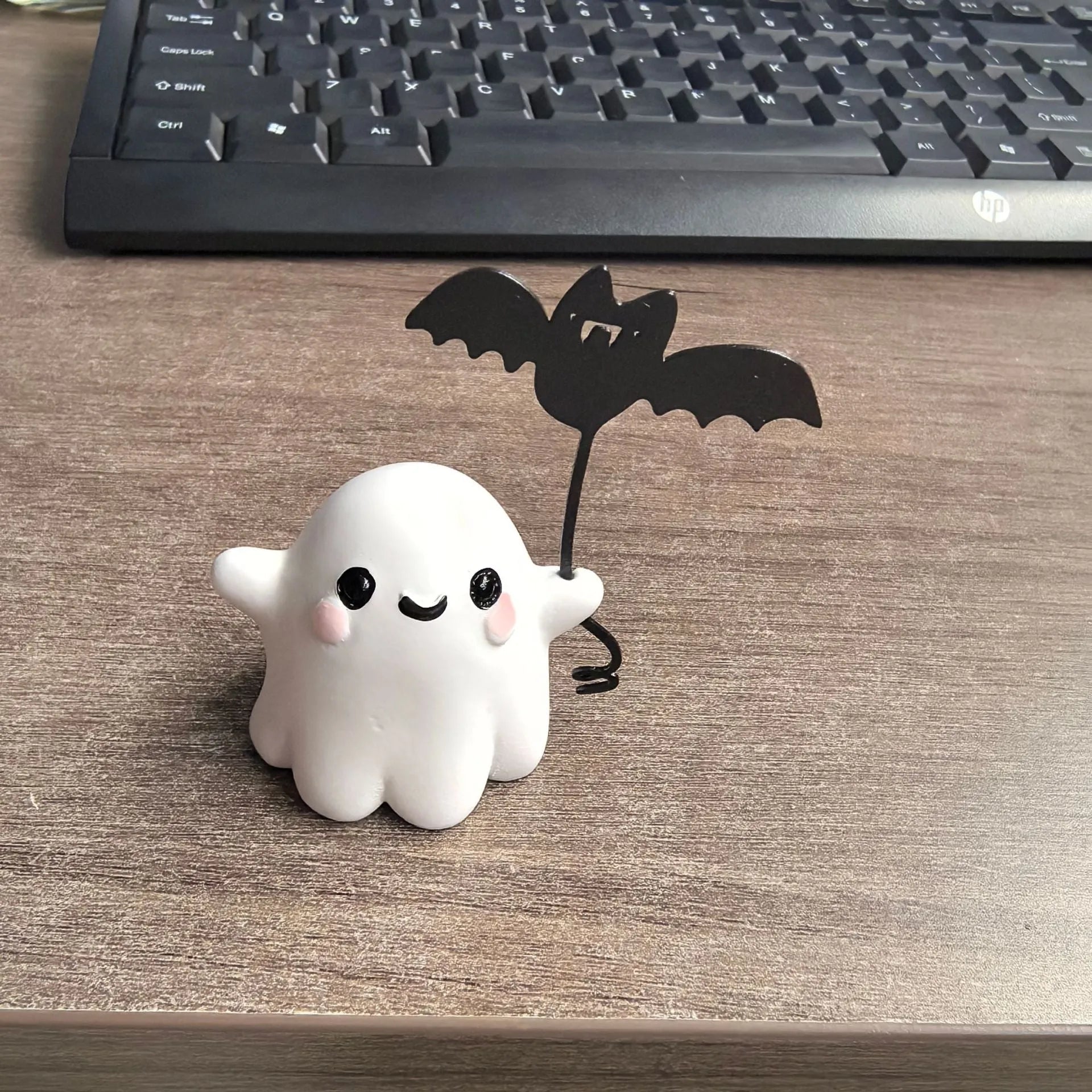 Small white resin statue of a ghost walking a bat on a Halloween lead