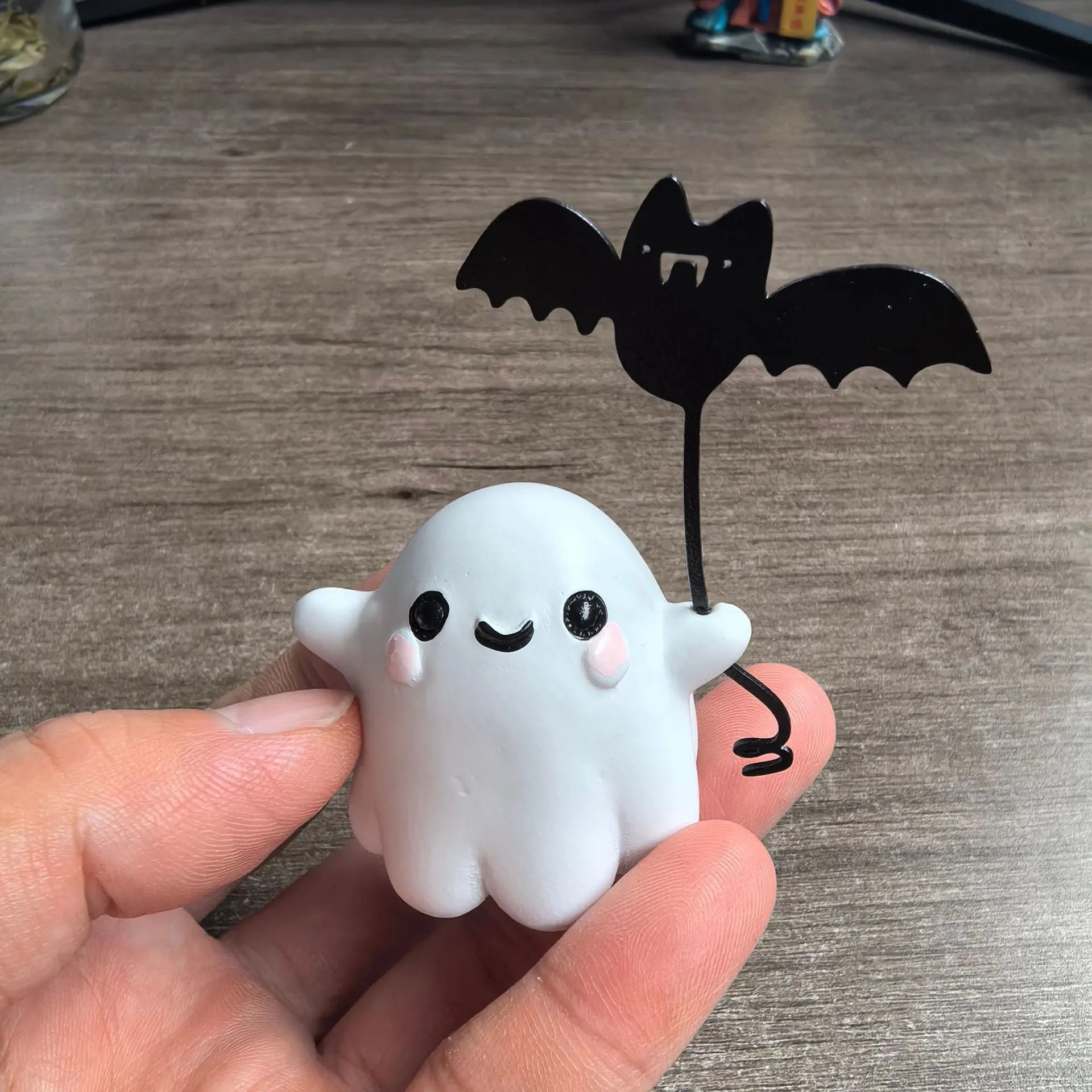 Small white resin statue of a ghost walking a bat on a Halloween lead