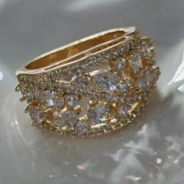 Women's round hollow fashion ring in gold or platinum plating with a central clear or blue crystal stone.