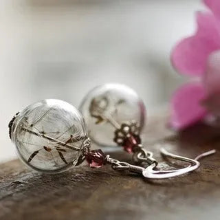 Close-up of a woman's ear wearing 16mm transparent glass ball dandelion seed earrings on a silver French hook.