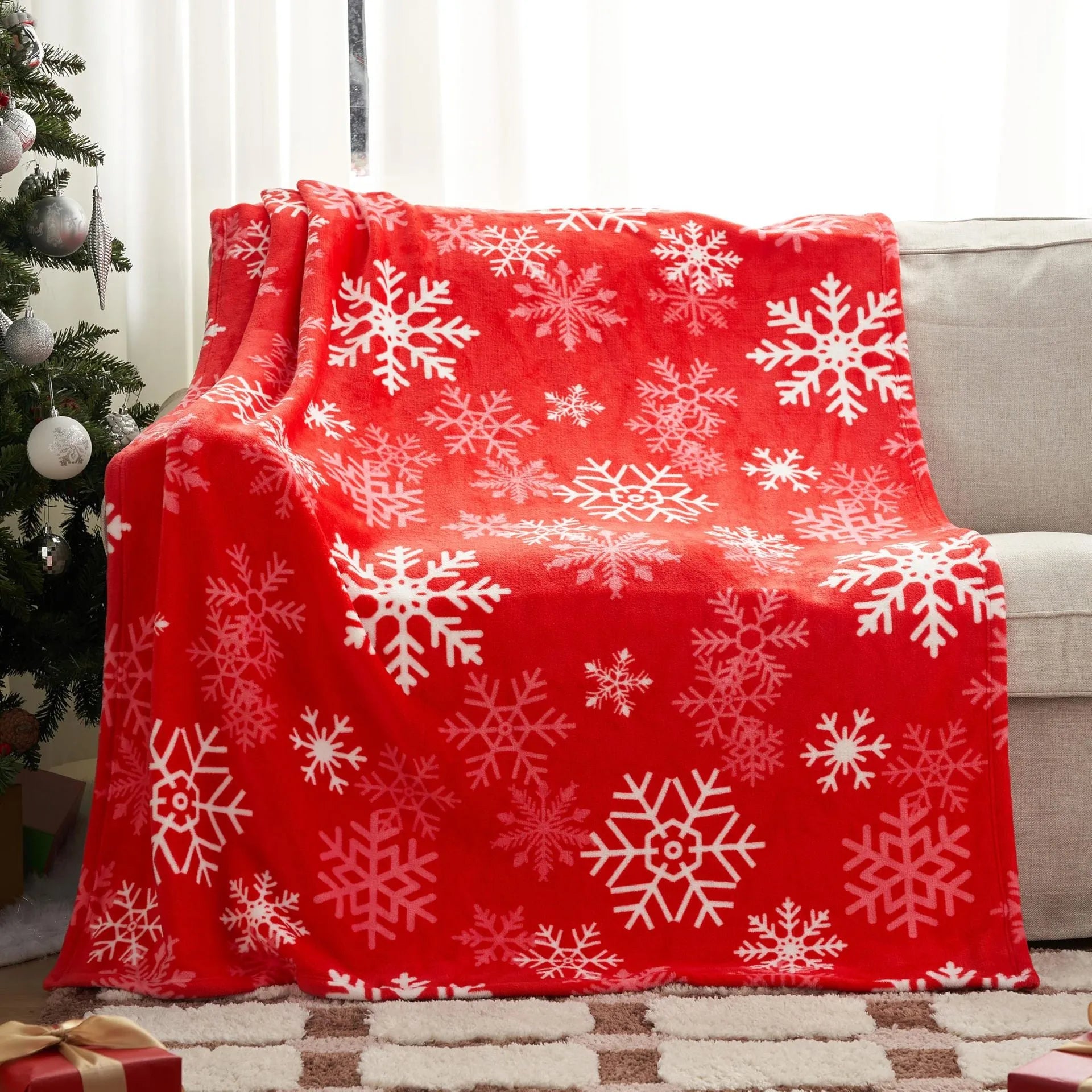 Soft flannel plush Christmas blanket in a choice of colours and multiple sizes on a sofa.