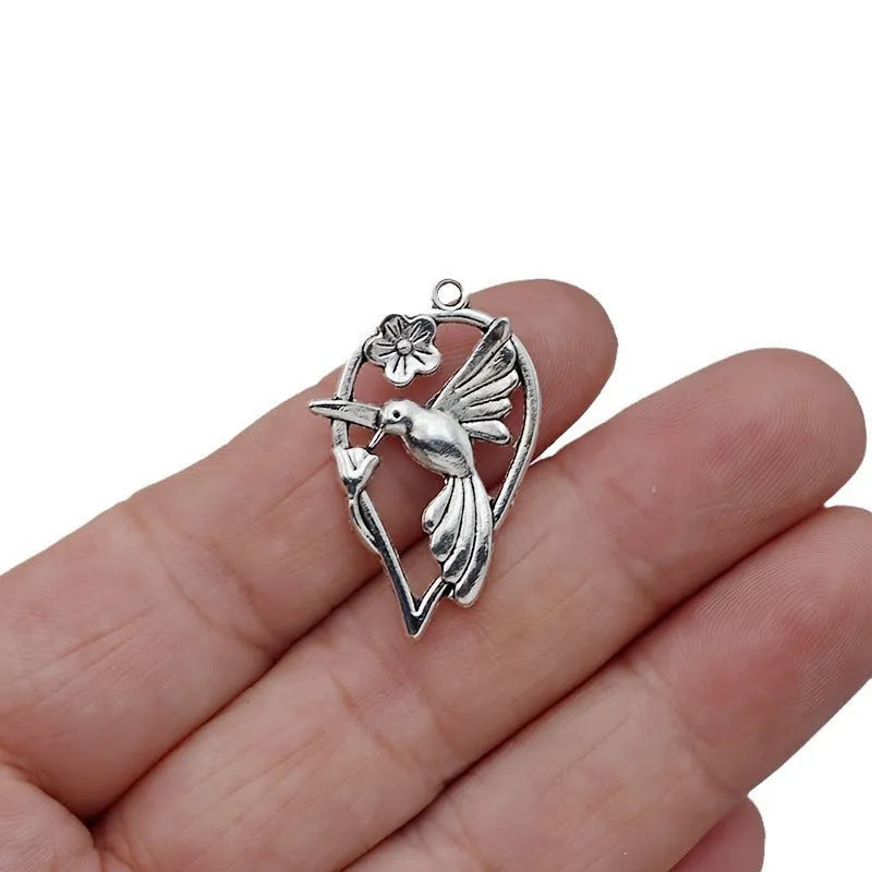 Close-up of a silver-grey alloy magpie pendant charm for DIY jewellery making on a white background.