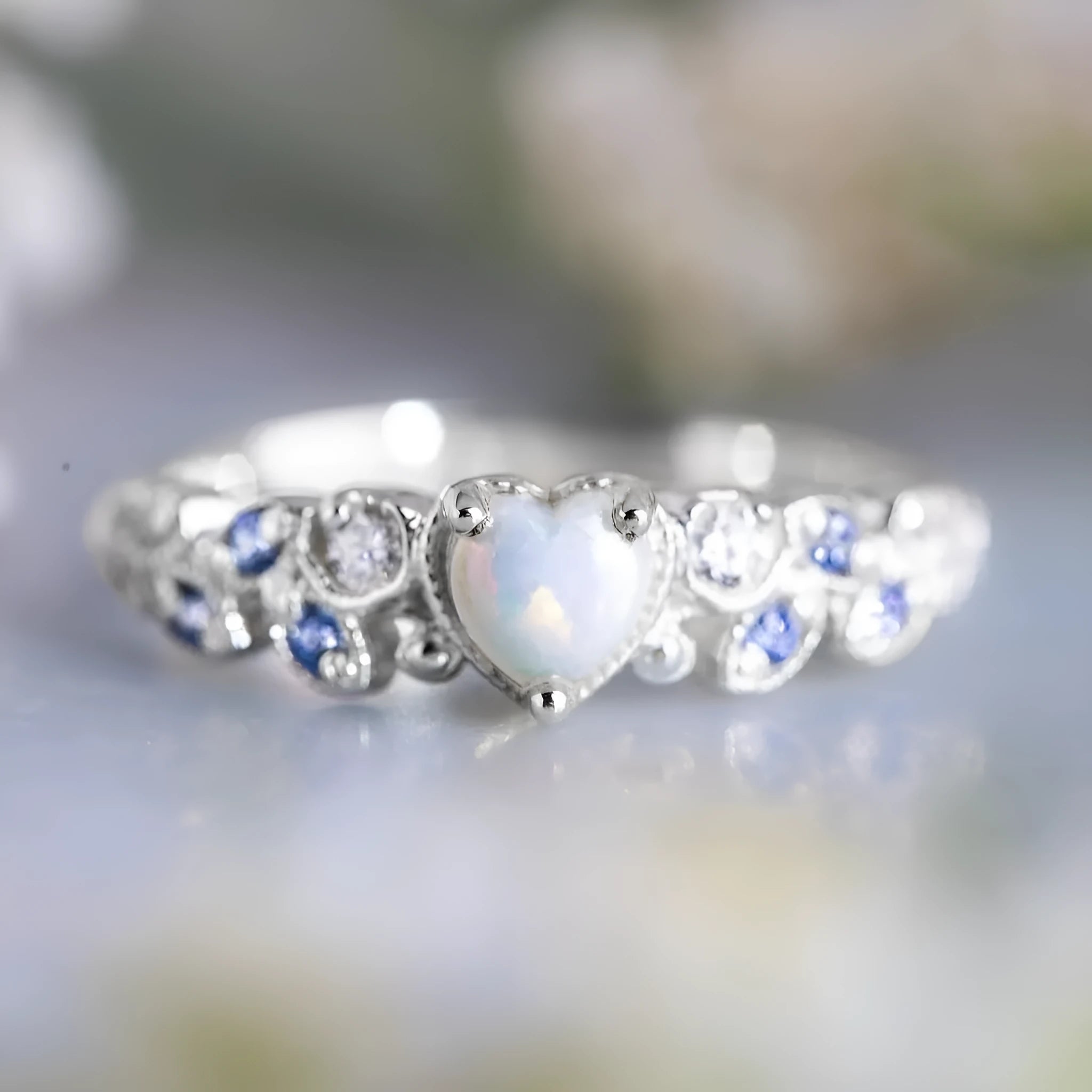 Close-up of a white alloy women's ring with a heart shape and flower opal ocean design.