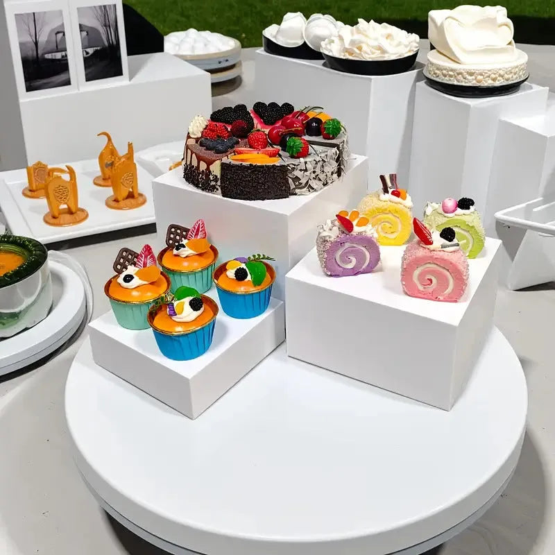 White plastic stacking cube dessert display stand set arranged in a pyramid for cakes and cupcakes.