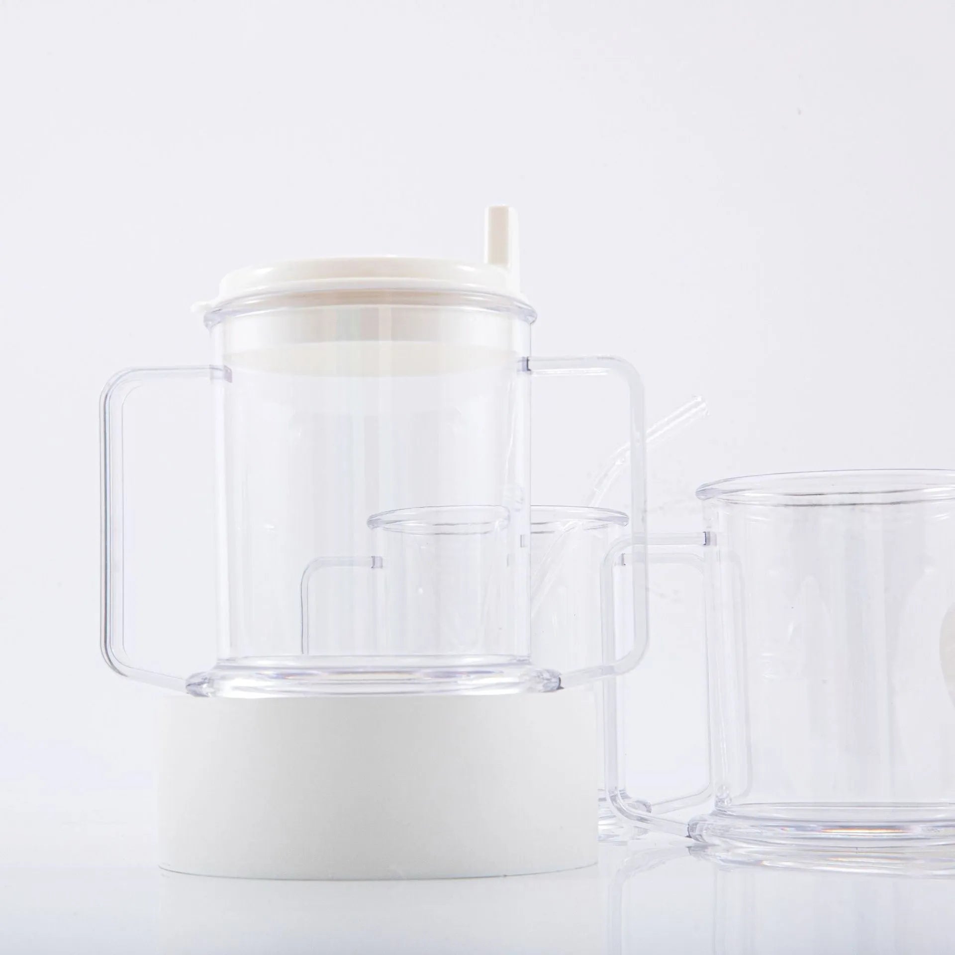 Transparent plastic drinking cup with spill-proof lid on a plain background.
