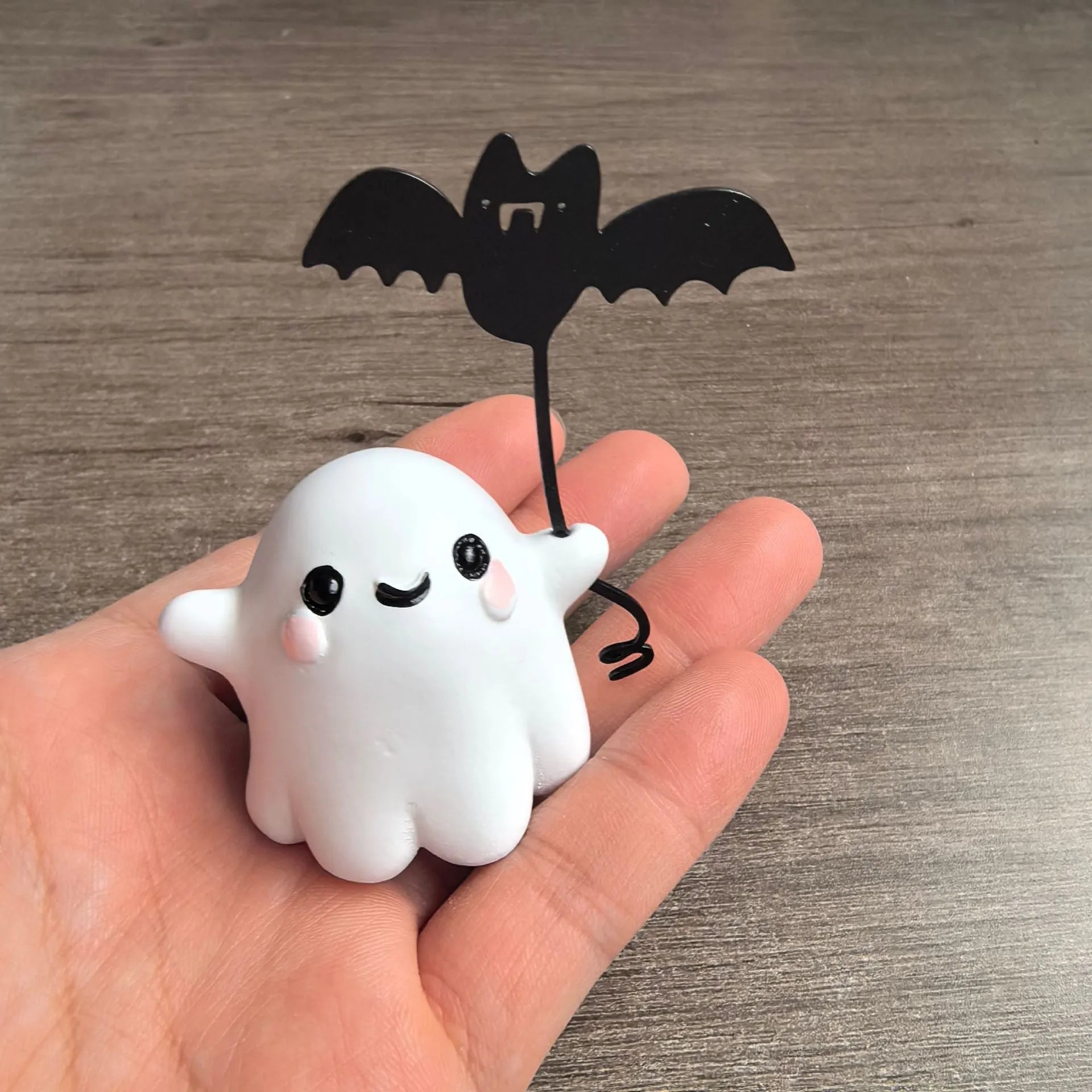 Small white resin statue of a ghost walking a bat on a Halloween lead
