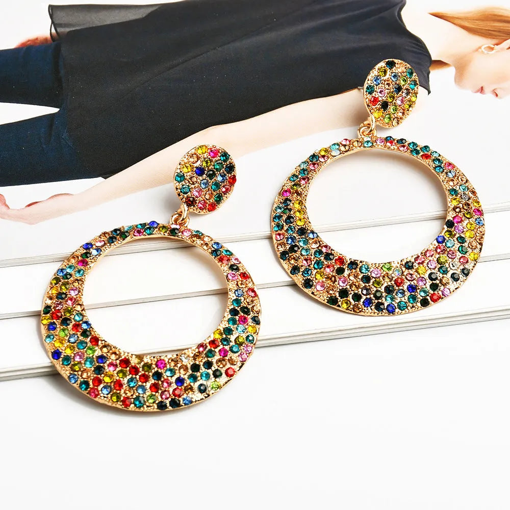 A pair of large round metal alloy pendant earrings with colourful cartoon diamond decorations.