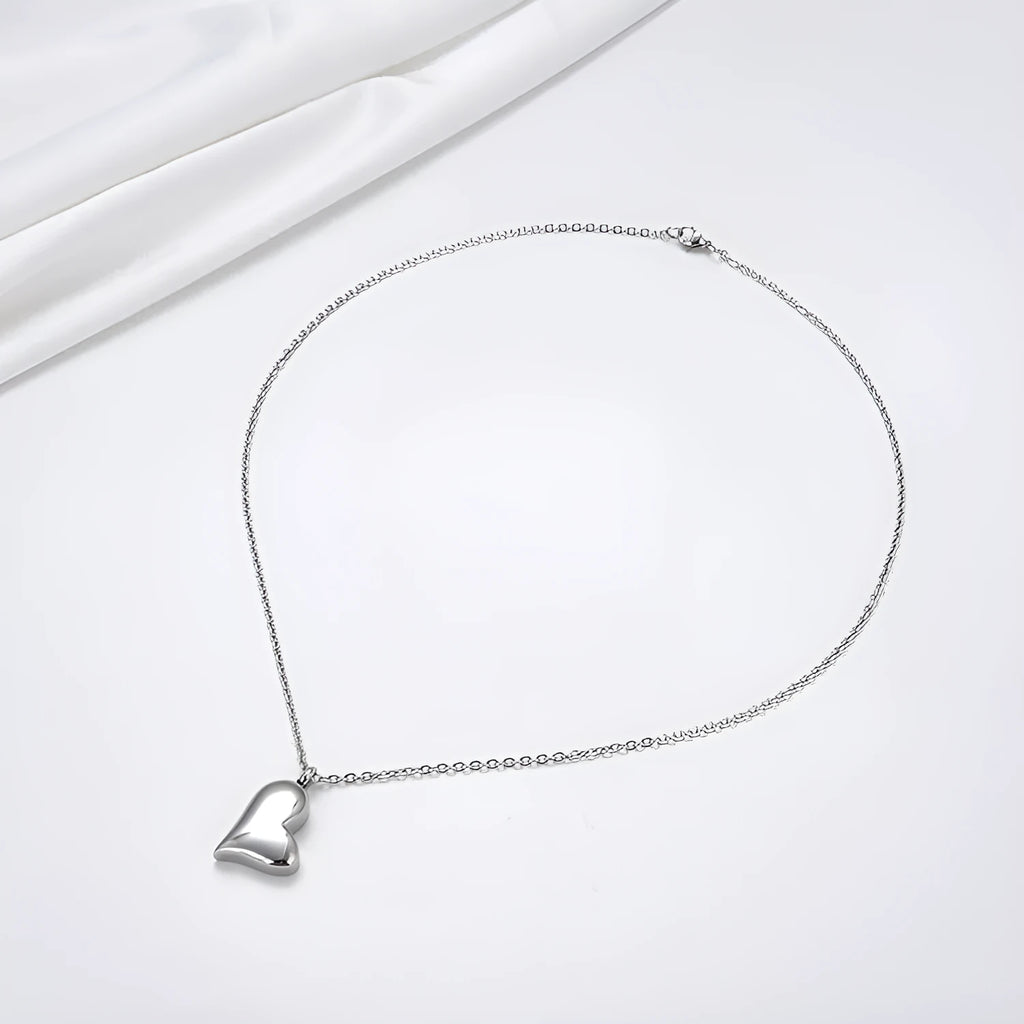 Silver curved peach heart pendant necklace with adjustable chain on grey background