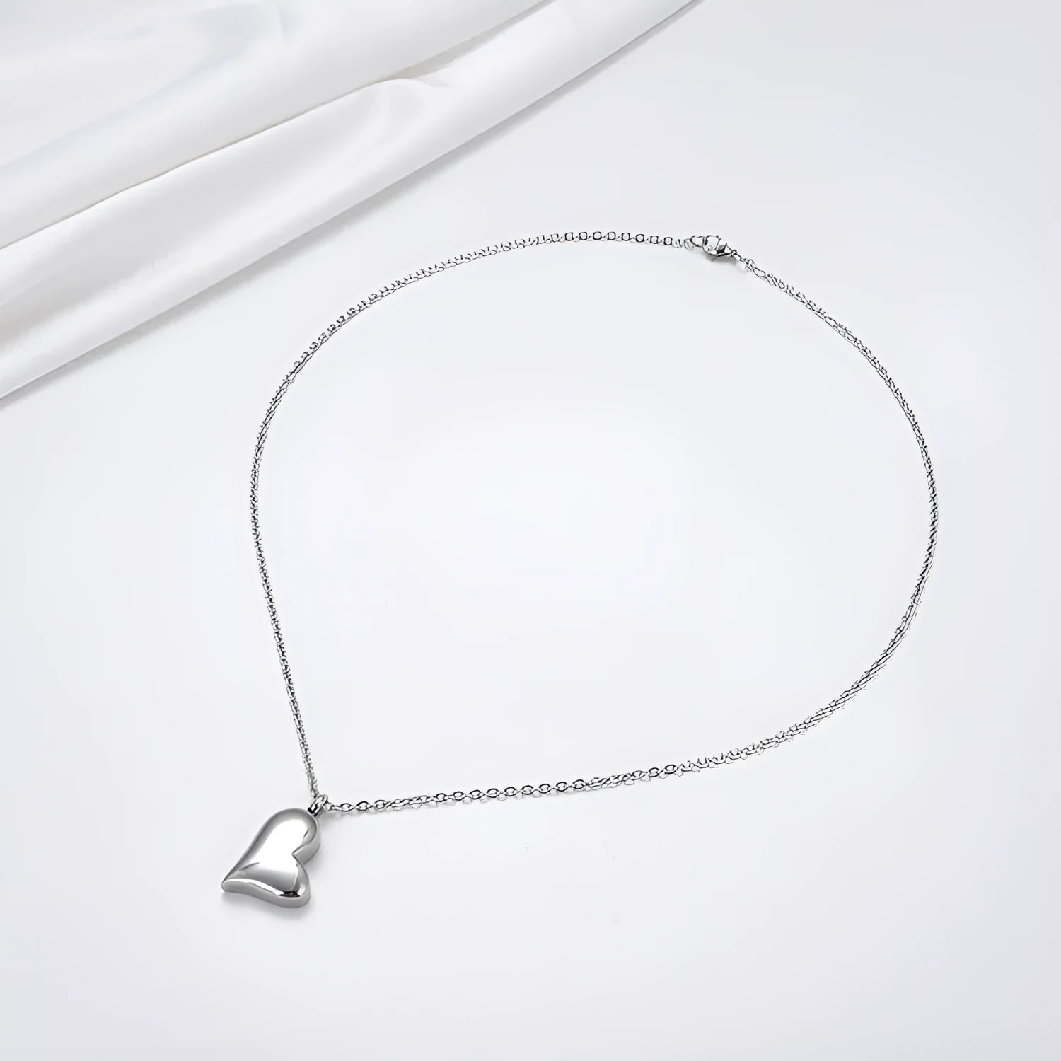Silver curved peach heart pendant necklace with adjustable chain on grey background