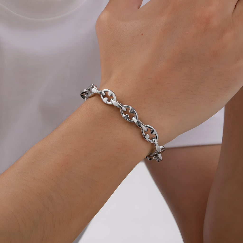 Thick stainless steel geometric link bracelet in steel colour on a wrist.