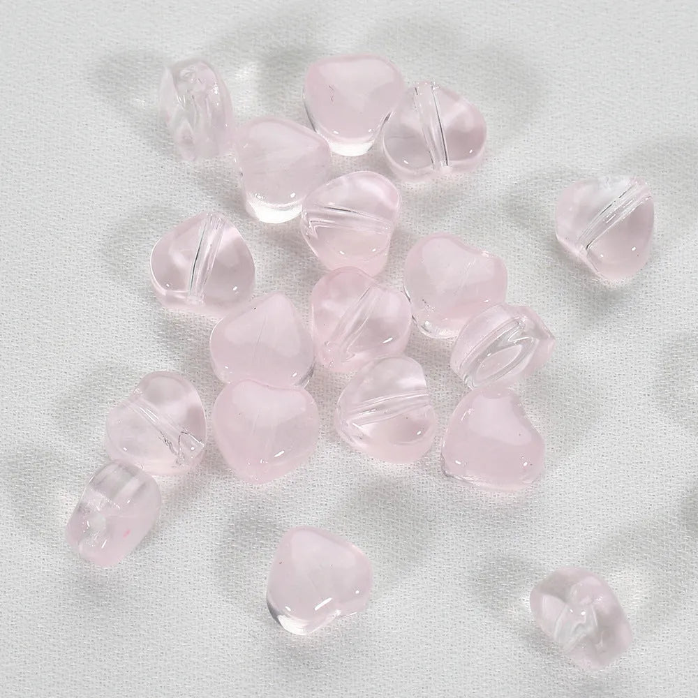 Twenty transparent love heart shaped spacer beads in assorted colours on a white background.