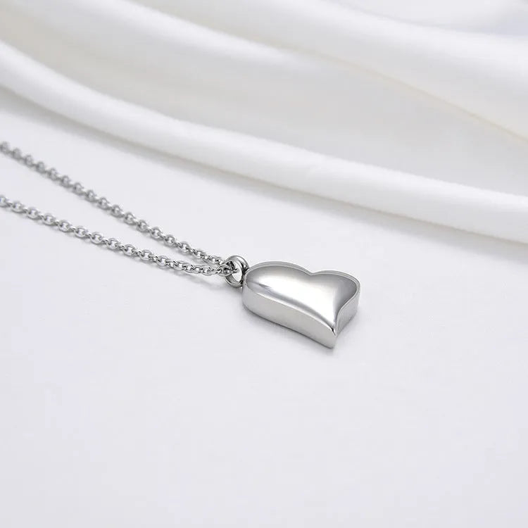 Silver curved peach heart pendant necklace with adjustable chain on grey background