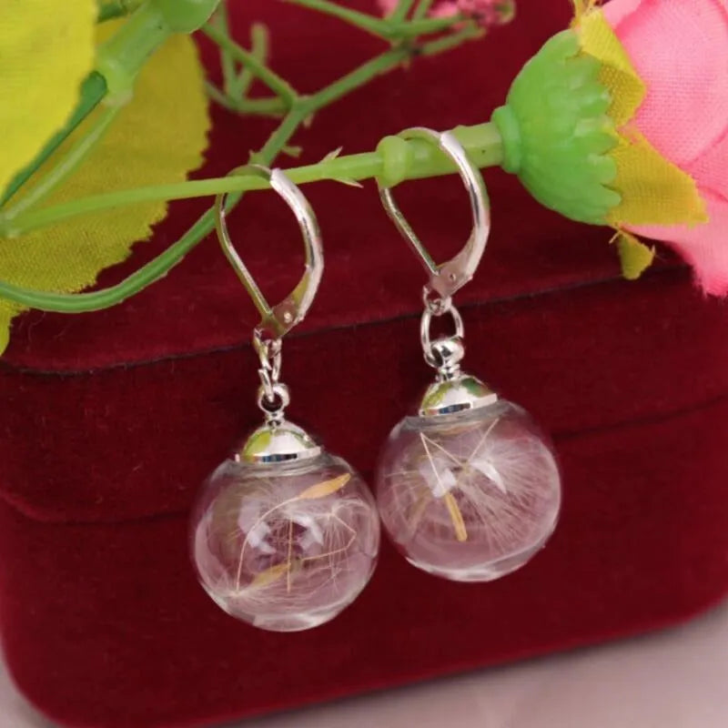 Close-up of a woman's ear wearing 16mm transparent glass ball dandelion seed earrings on a silver French hook.