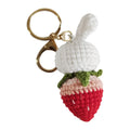 White hand-woven wire pendant with a cartoon rabbit and strawberry design, shown with a metal key.