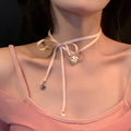 Close-up of a women's alloy fashion necklace with a ribbon love pendant on a dainty clavicle chain.
