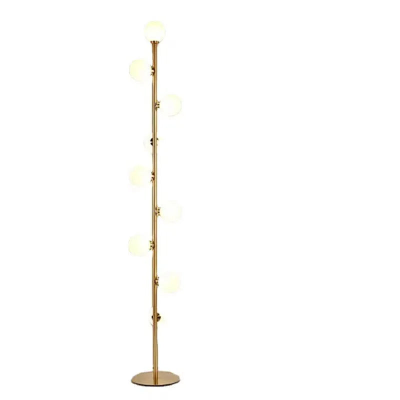 Tall modern floor lamp with slender iron frame, glass shade, and solid circular base in a minimalist living room setting.