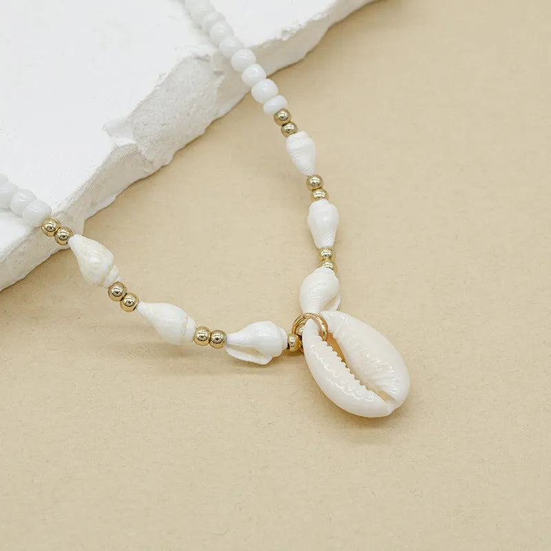 White conch-shaped mother pearl shell pendant necklace on a regular chain for women.