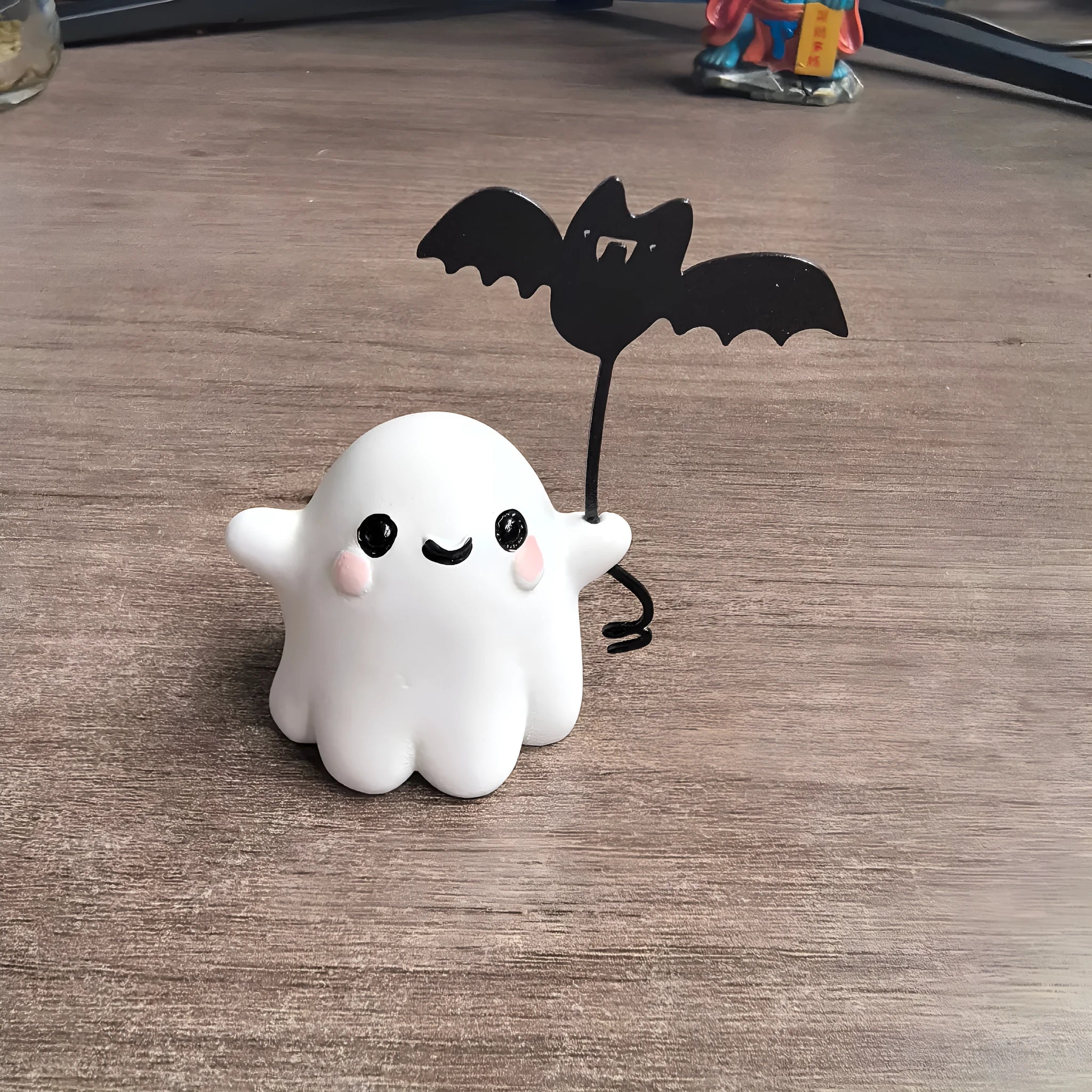 Small white resin statue of a ghost walking a bat on a Halloween lead