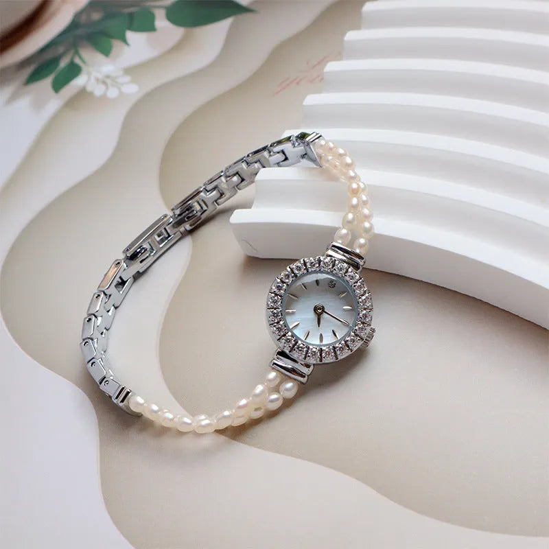 Women's light gold bracelet watch with freshwater pearls, showing 18mm round dial and stainless steel strap.