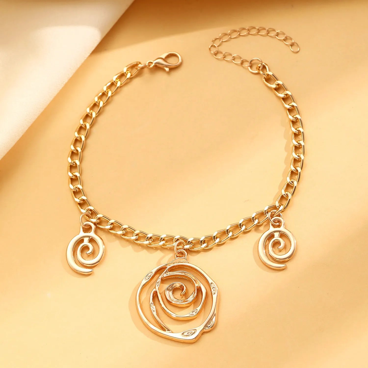 Spiral donut jewellery set showing necklace, bracelet and ear hooks with geometric circle designs in gold finish