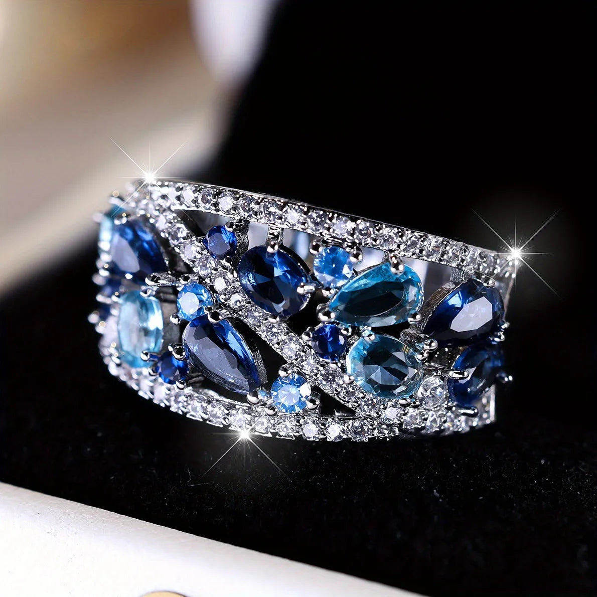 Women's round hollow fashion ring in gold or platinum plating with a central clear or blue crystal stone.