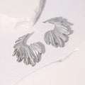 A pair of stainless steel stud earrings in a leaf shape, shown in gold colour and steel colour finishes.