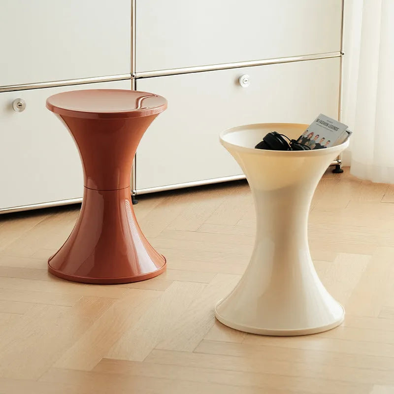 Plastic hourglass-shaped shoe changing stool shown in green, placed on a wooden floor.