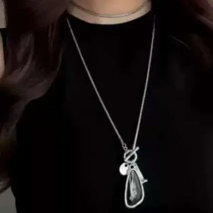 Geometric alloy pendant with plaid pattern on a long snake bones chain necklace.