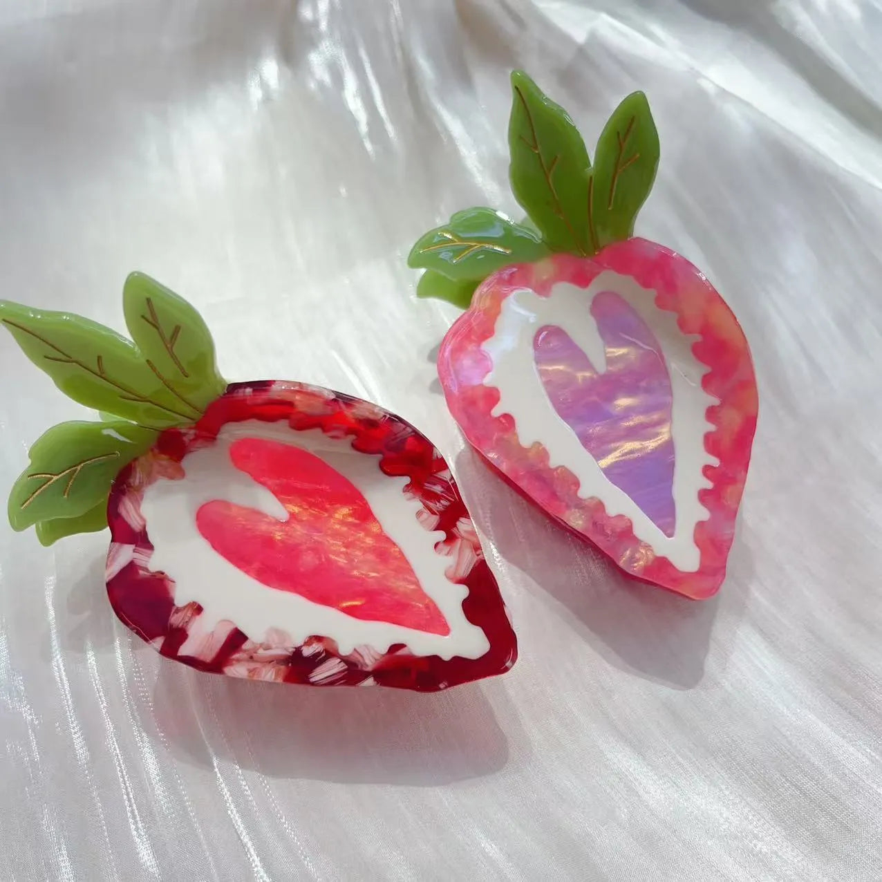Close-up of a handmade strawberry decorative hair clip on a pink background.