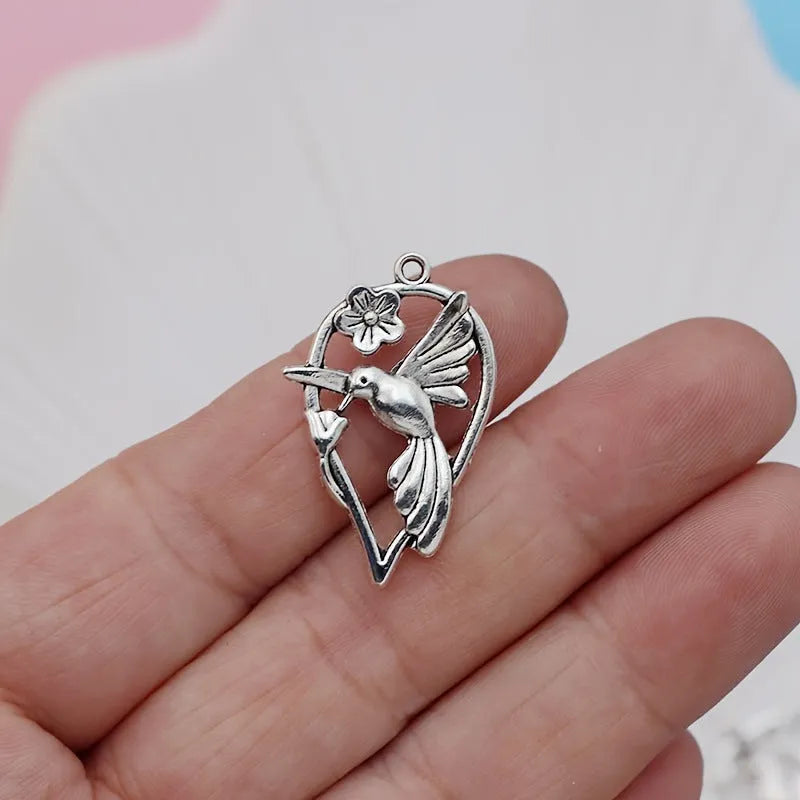 Close-up of a silver-grey alloy magpie pendant charm for DIY jewellery making on a white background.