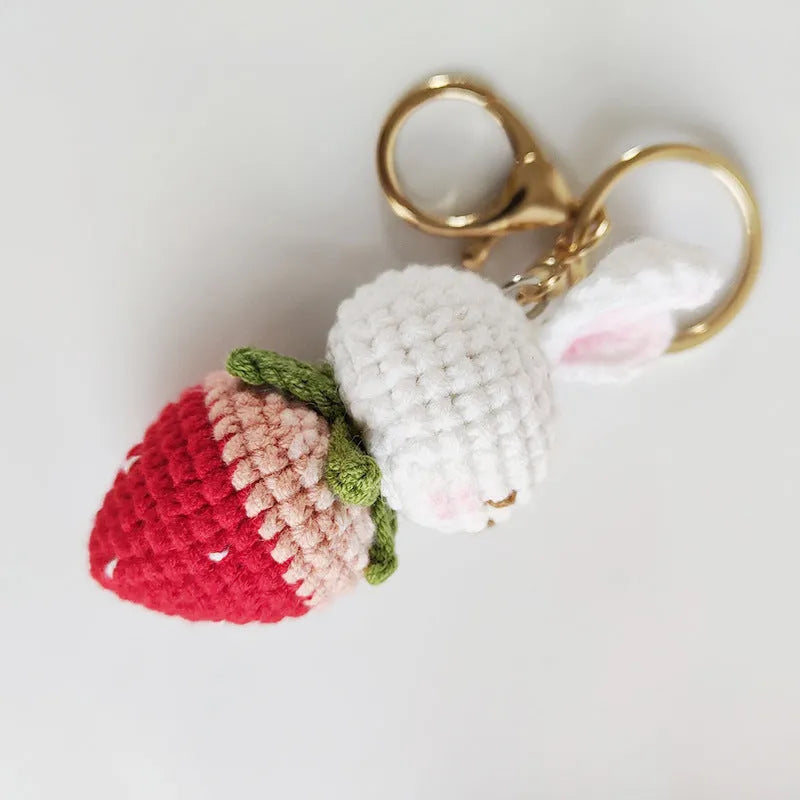 White hand-woven wire pendant with a cartoon rabbit and strawberry design, shown with a metal key.