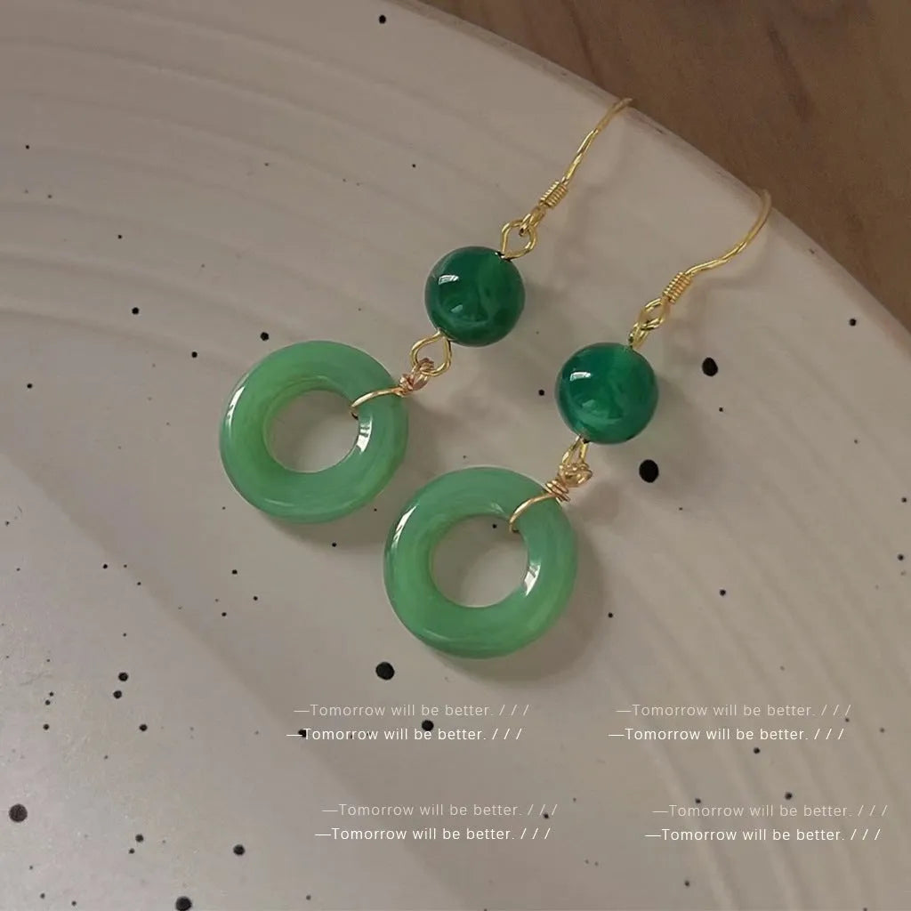 A pair of geometric peace buckle earrings with a green jade design and gold plating.