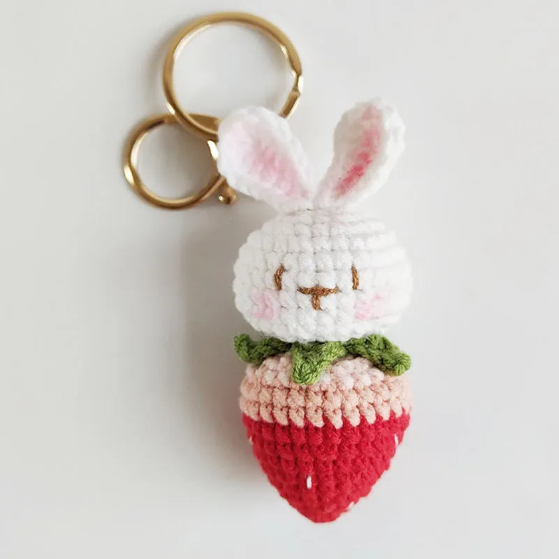 White hand-woven wire pendant with a cartoon rabbit and strawberry design, shown with a metal key.
