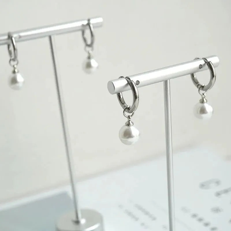 A pair of geometric-style pearl earrings for women with titanium steel posts.