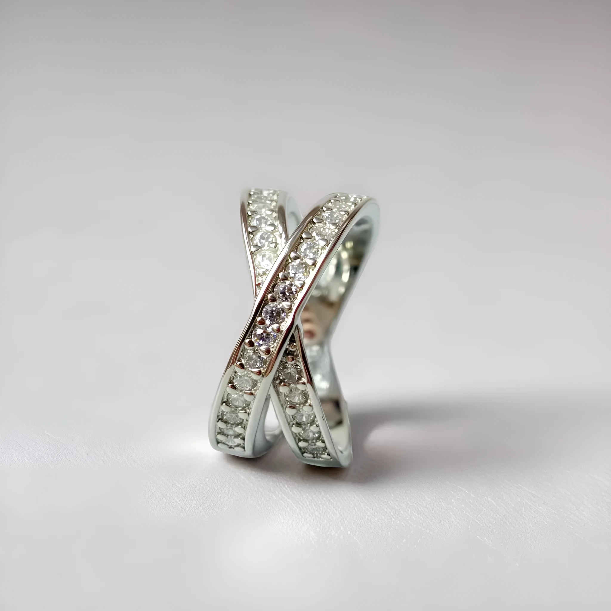 Geometric heart-shaped cross ring with a micro-inlaid zircon stone in a silver or rose gold electroplated finish.