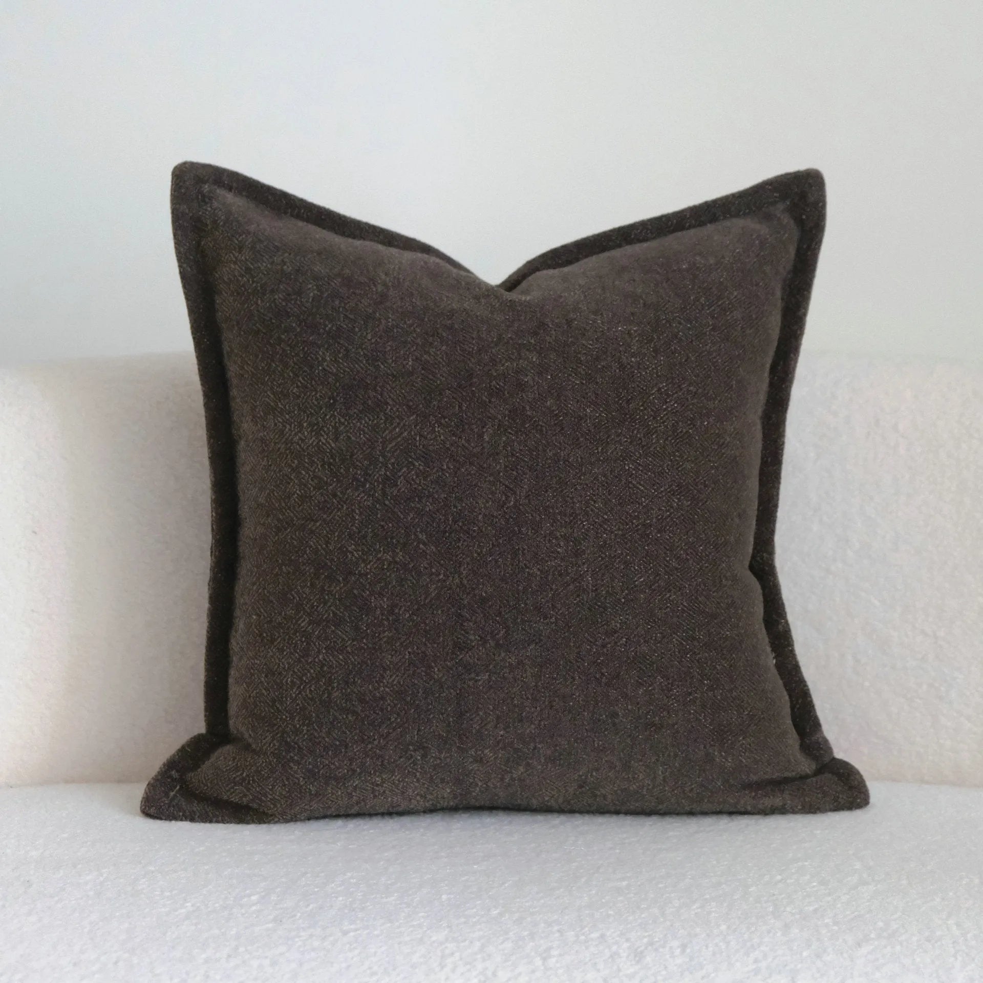 Coffee brown Chinese classical style cushion with striped and patchwork designs on a sofa.