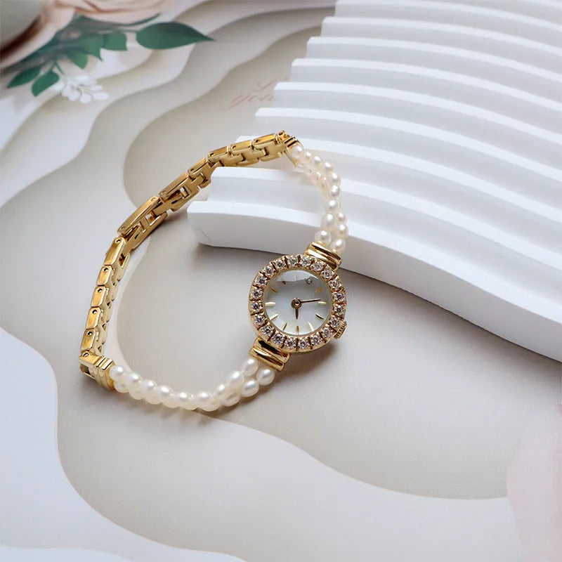 Women's light gold bracelet watch with freshwater pearls, showing 18mm round dial and stainless steel strap.