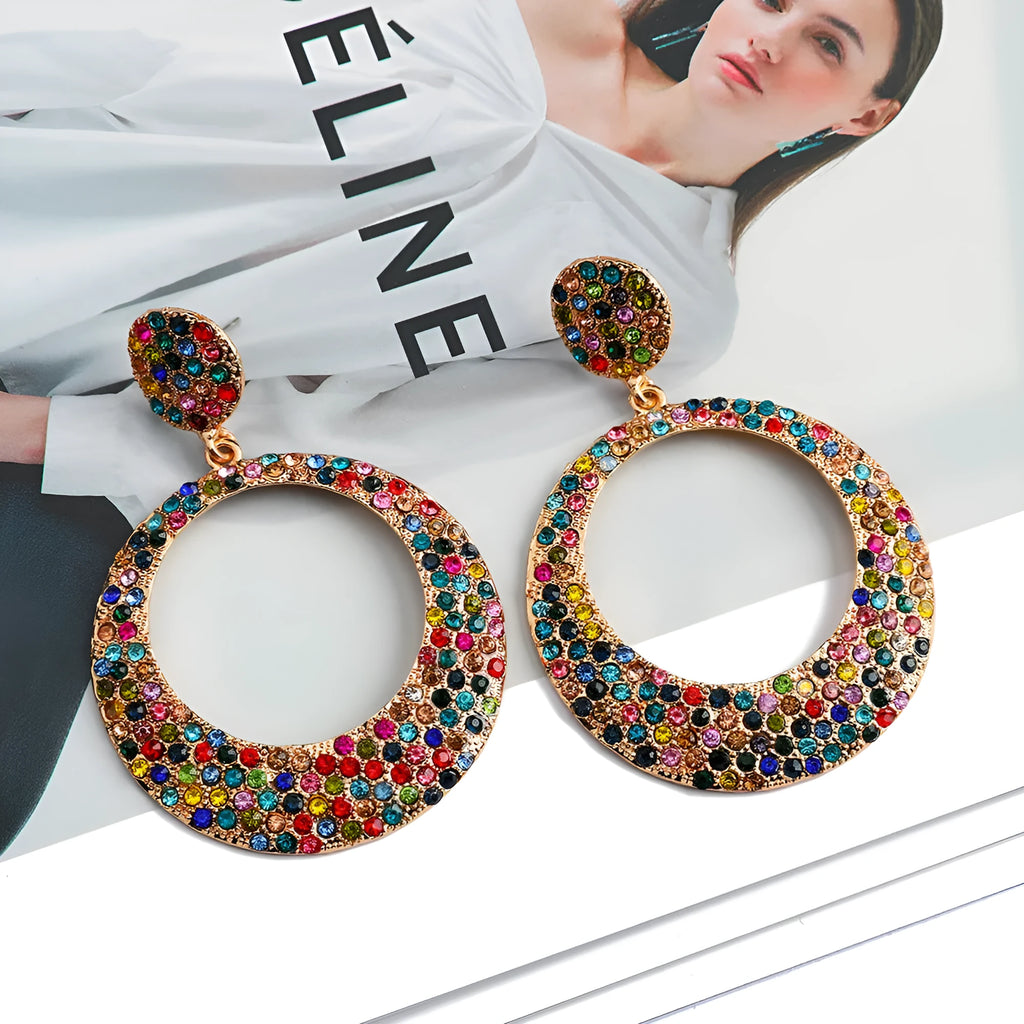A pair of large round metal alloy pendant earrings with colourful cartoon diamond decorations.