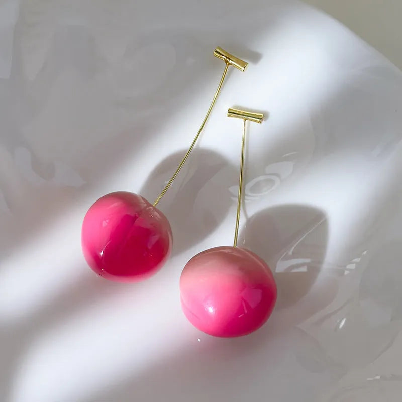 A pair of acrylic peach fruit earrings on copper posts, shown in small and large size options.
