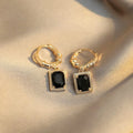 Close-up of black geometric cubic zirconia earrings with a quadrilateral design and butterfly clutch backs.