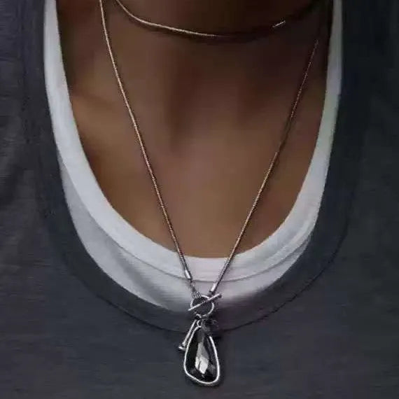 Geometric alloy pendant with plaid pattern on a long snake bones chain necklace.
