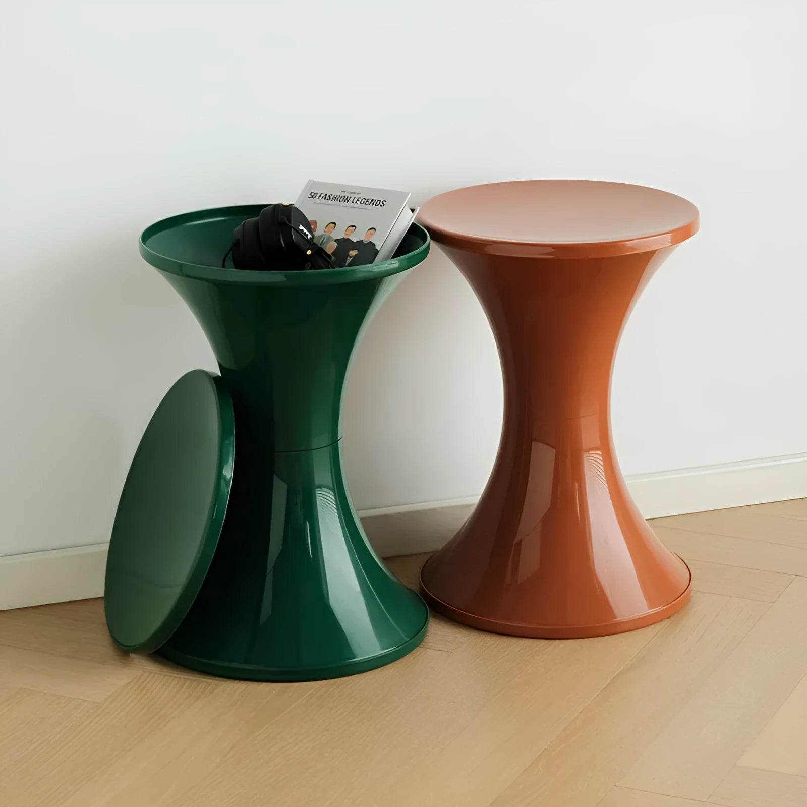 Plastic hourglass-shaped shoe changing stool shown in green, placed on a wooden floor.
