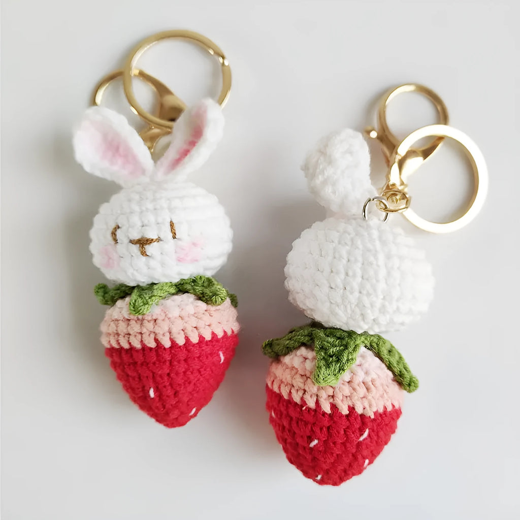 White hand-woven wire pendant with a cartoon rabbit and strawberry design, shown with a metal key.
