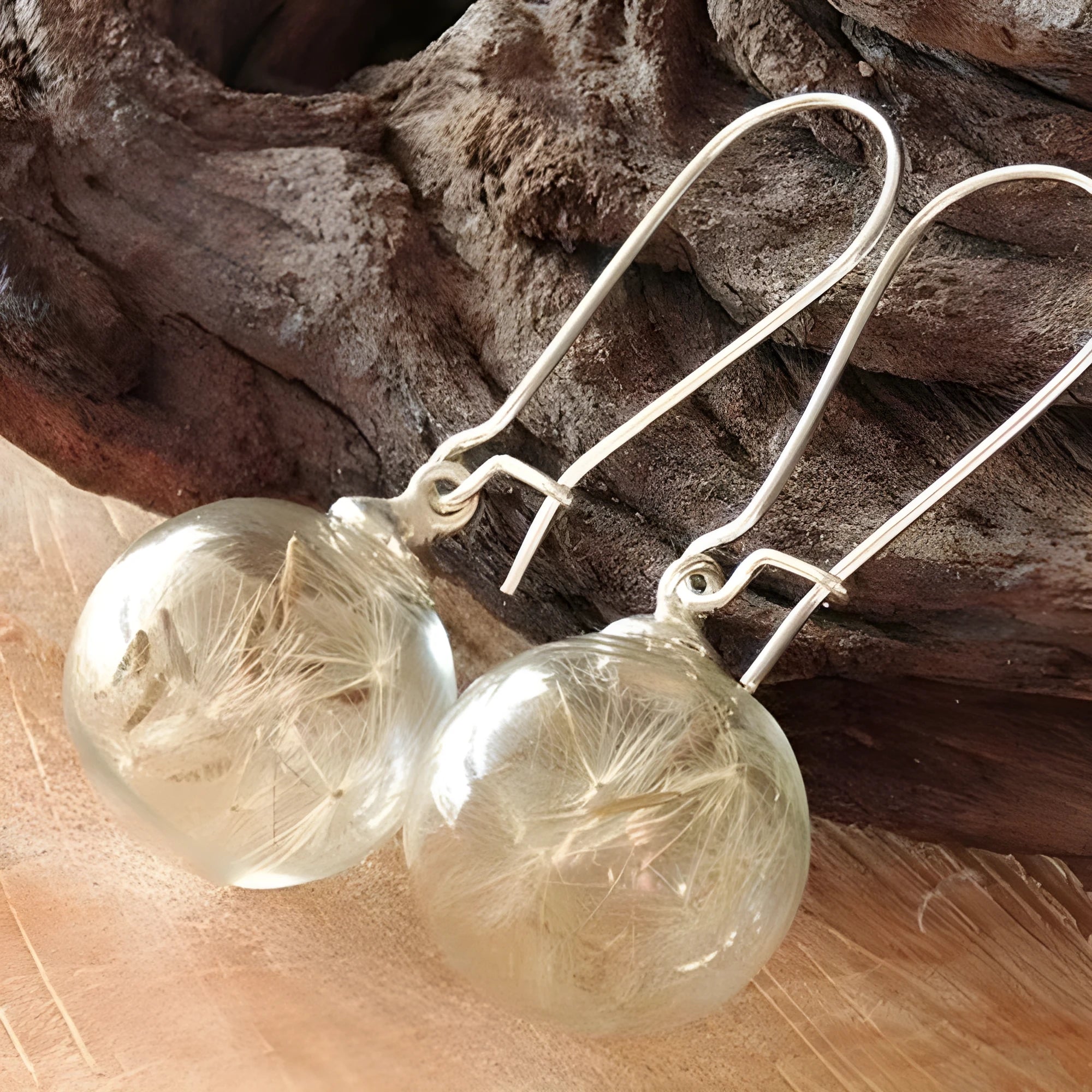 Close-up of a woman's ear wearing 16mm transparent glass ball dandelion seed earrings on a silver French hook.